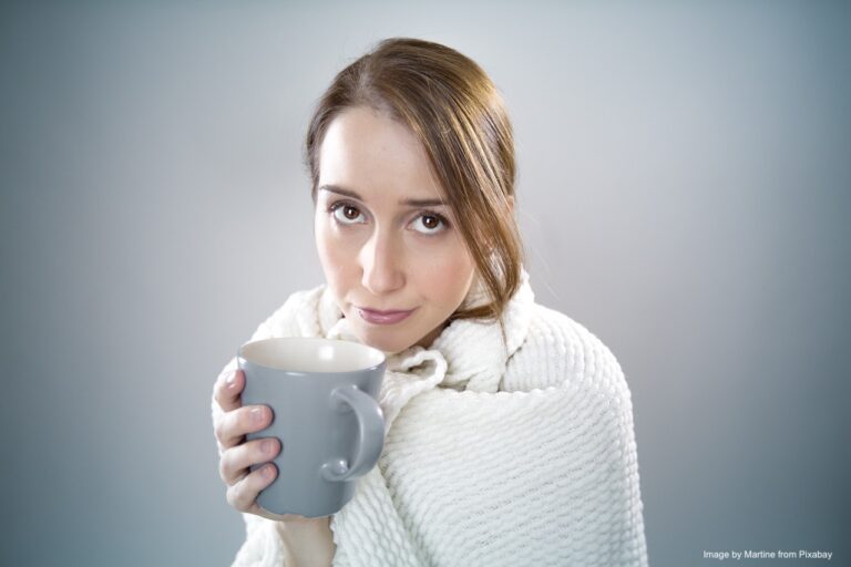 A sick woman drinking a hot drink